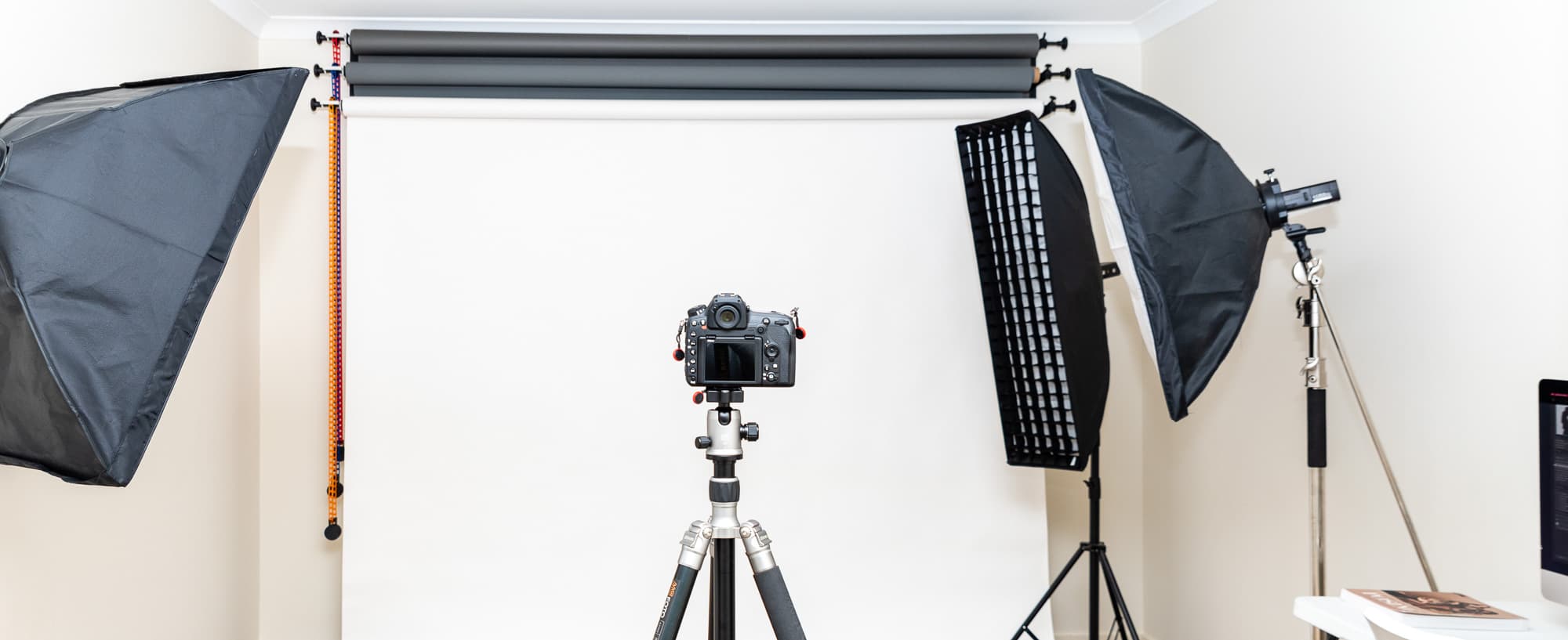 Chamara Perera Photography studio setup with white backdrop, softboxes, and camera on tripod used for professional photography sessions, providing a comfortable and versatile environment for capturing high-quality photos.